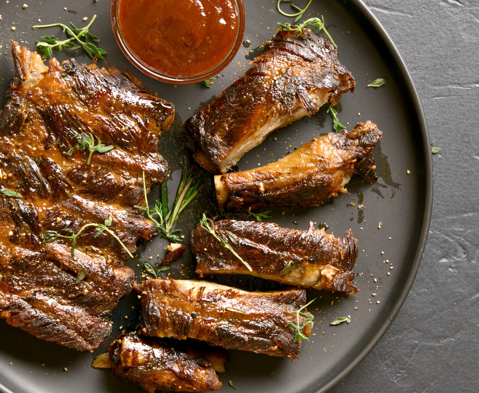 Bbq ribs on plate over black stone background. Tasty bbq meat. Top view, flat lay