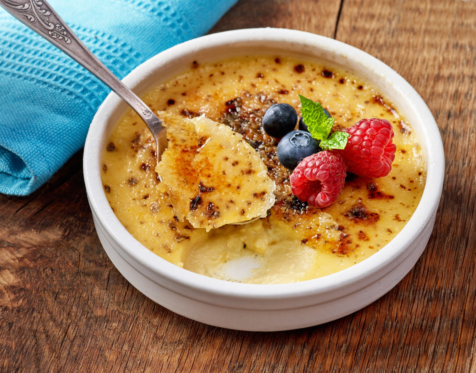 bowl of homemade creme brule with fresh berries on wooden table