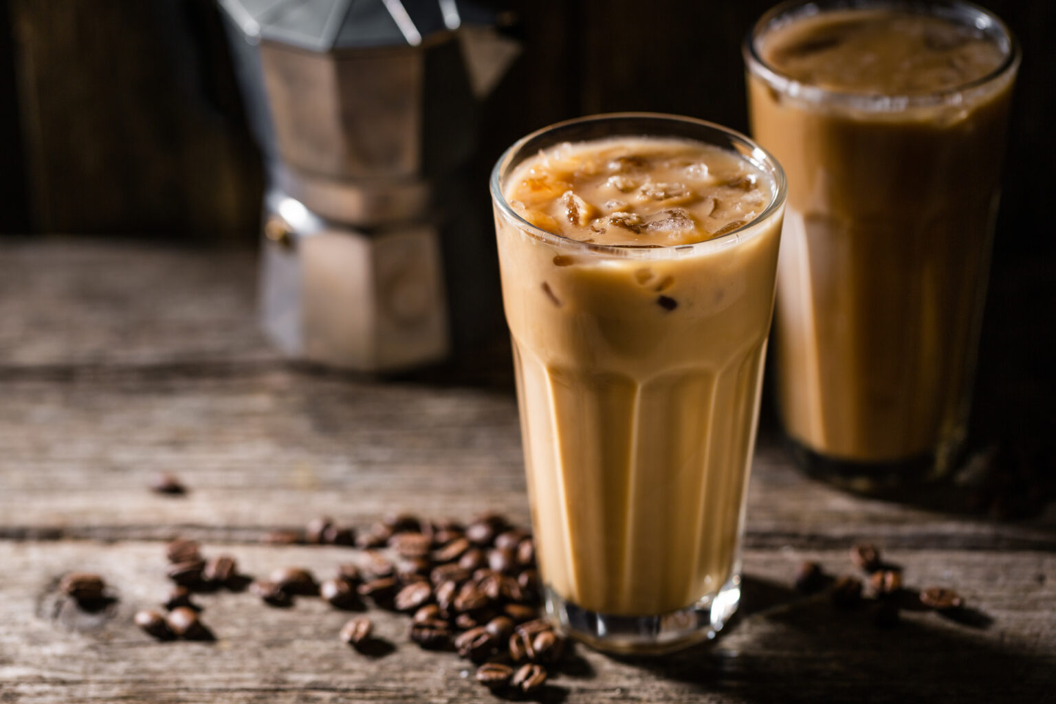 Tasty appetizing refreshing cold coffee with ice and cream milk in glasses. Ready for drinking. Served on old wooden table.