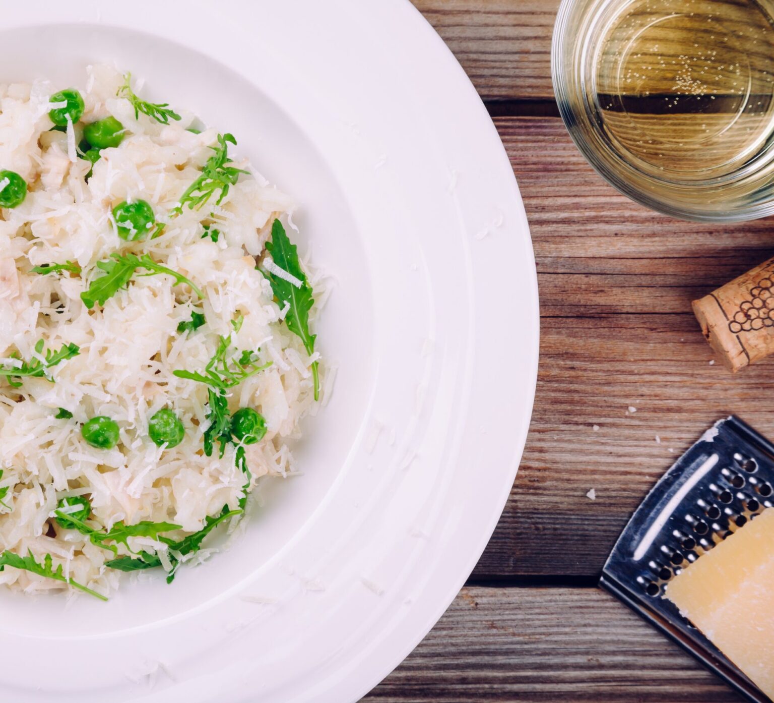 Homemade risotto with chicken, green peas, arugula and parmesan. top view