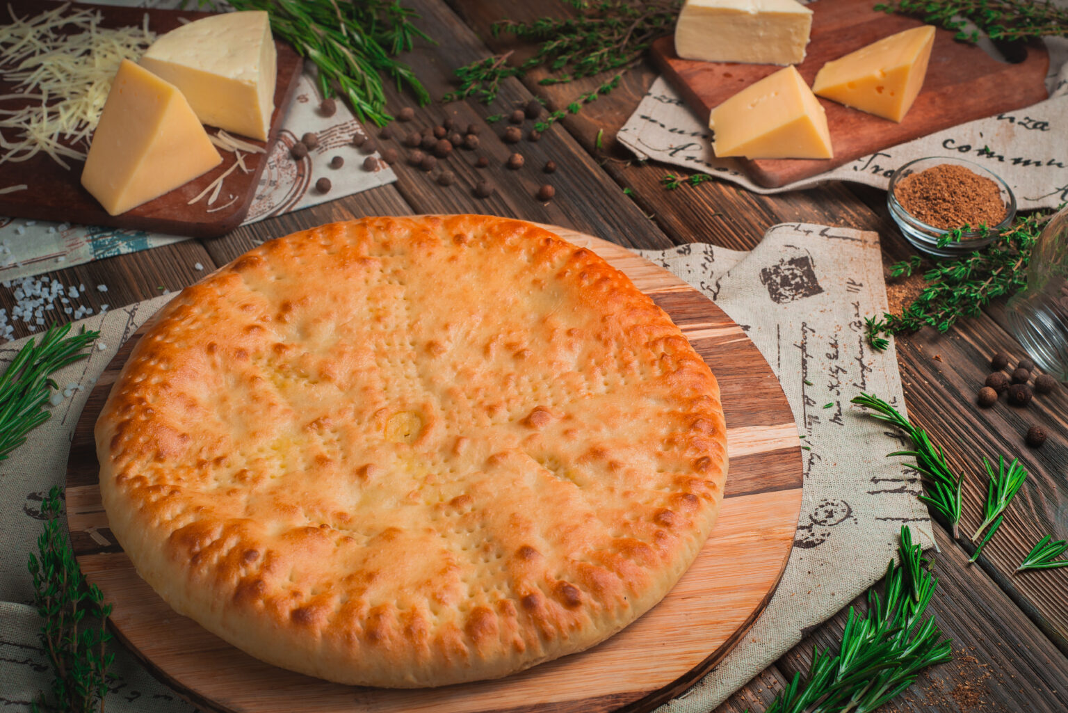 Homemade savory pie filled with cheese on a wooden kitchen table with ingredients. Traditional baking concept. Delivery menu with copy space
