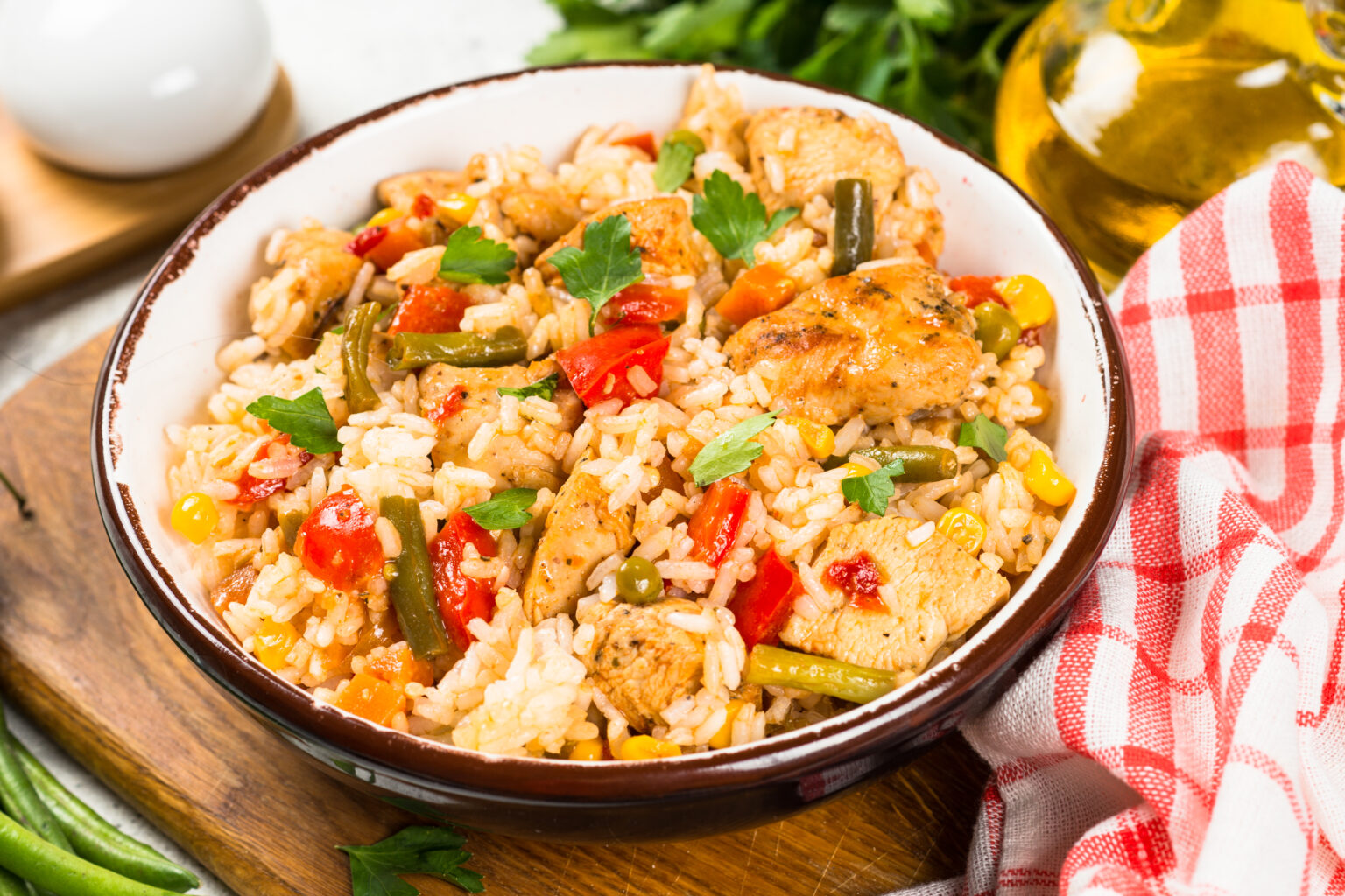 Rice with chicken and vegetables in craft plate on white stone table.