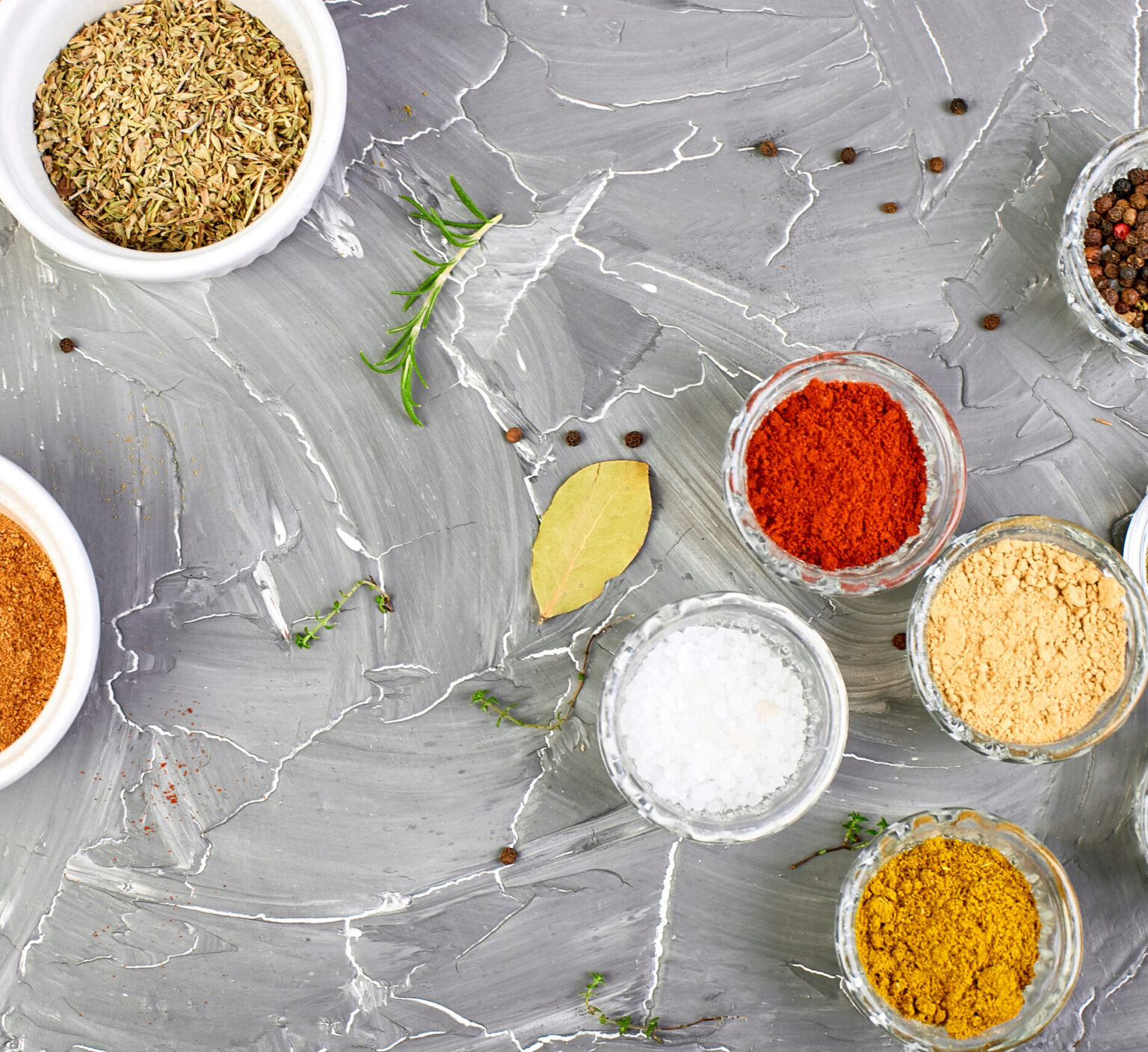 Seasoning background. Spice and herb seasoning with fresh and dried herbs and spices in bowls. Colourful various herbs and spices for cooking on grey background. Top view. Copy space.