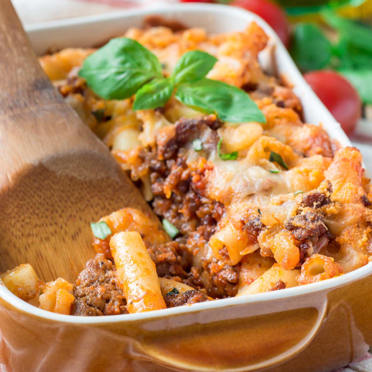 Ziti bolognese in baking dish, pasta casserole with minced meat, tomato sauce and cheese, square format