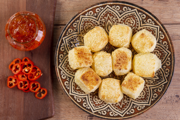 Tapioca dice served with pepper jelly. Wooden table.