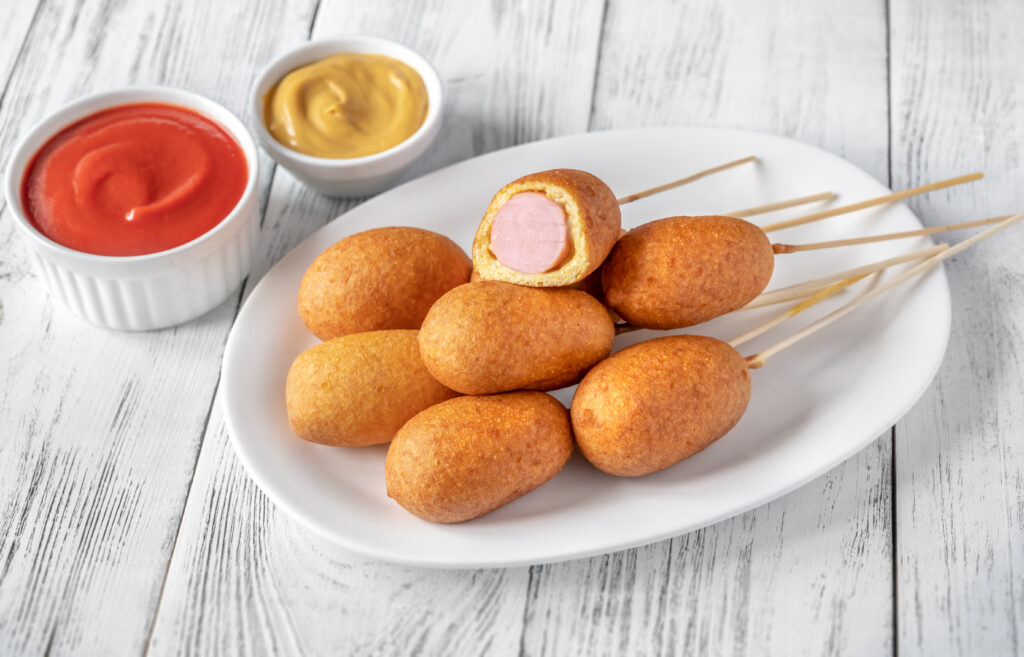 Corn dogs on white serving plate